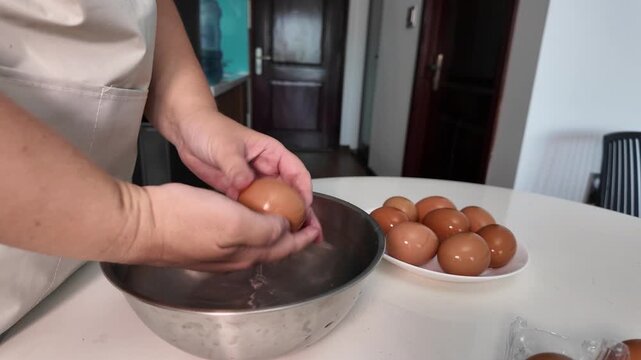 Woman washes chicken eggs in a metal bowl