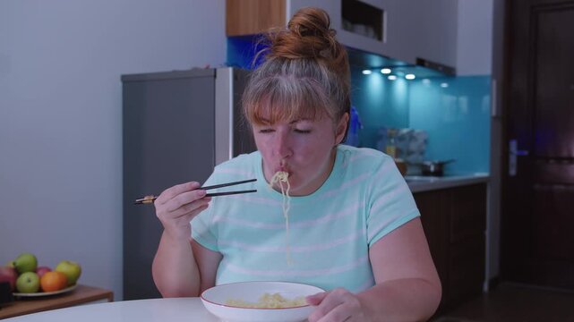 Portrait of a woman who eats simple ramen noodles with chopsticks from a cup