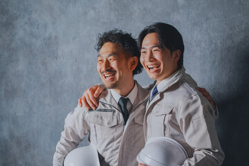 肩を組む作業着姿の男性