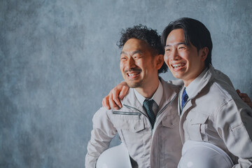 肩を組む作業着姿の男性