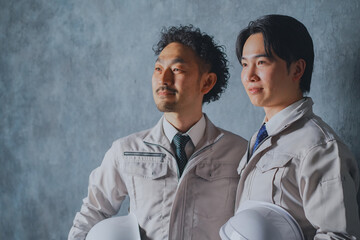 ヘルメットを持った作業着姿の男性