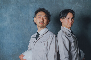 ヘルメットを持った作業着姿の男性