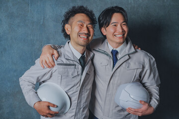 肩を組む作業着姿の男性
