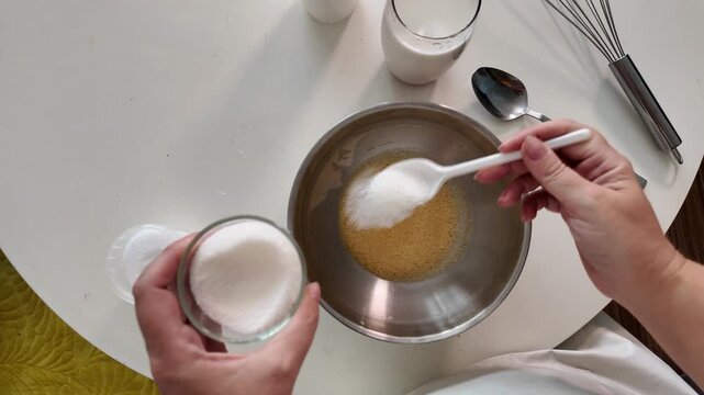The woman adds sugar and salt to the beaten eggs. Makes morning pancakes