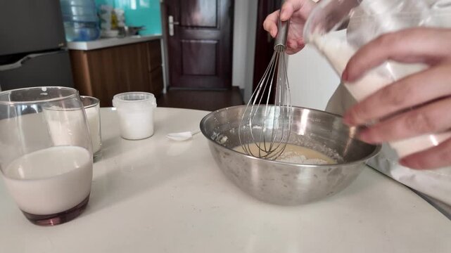 The woman adds the ingredients for cooking the dish to the beaten eggs, whips them with a whisk
