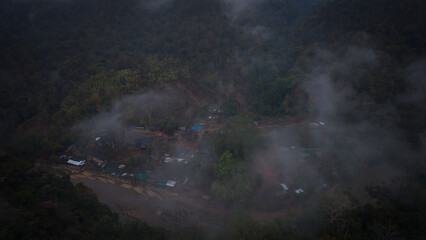 Aerial view of a small village with cute wooden houses and a road on the coast of meadows with large green rivers and big mountains.