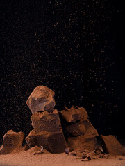 Chocolate pieces with chocolate chips and cocoa sprinkles on dark background