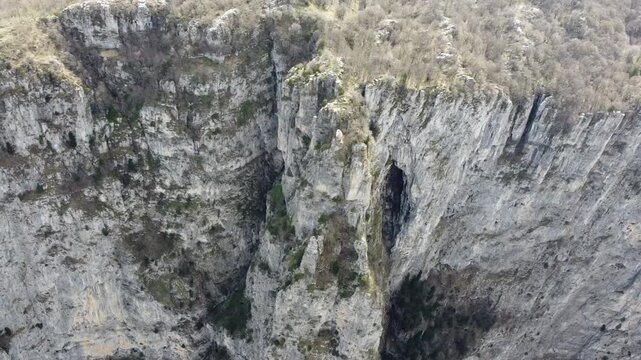 A cinematic drone close-up of the towering limestone walls of Vikos Gorge. Highlighting the jagged rock textures and the sheer verticality of the world's deepest canyon in Epirus, Greece.