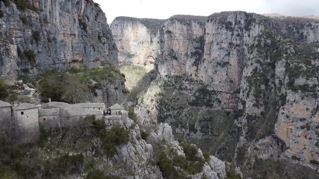 A cinematic drone view of the 15th-century Monastery of Saint Paraskevi, perched on the edge of Vikos Gorge near Monodendri village. A spiritual sanctuary with breathtaking canyon views.