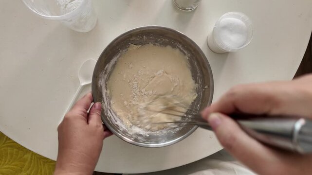 The woman added the ingredients to the batter and whipped the mixture with a whisk