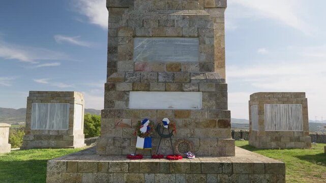 Cinematic upward tilt revealing the Doiran World War One Memorial with lion sculptures and marble engraved names honoring British and Commonwealth soldiers near the Macedonia border