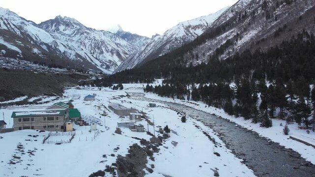 Forward moving aerial drone shot over snow covered Himalayan mountains in Chitkul, India