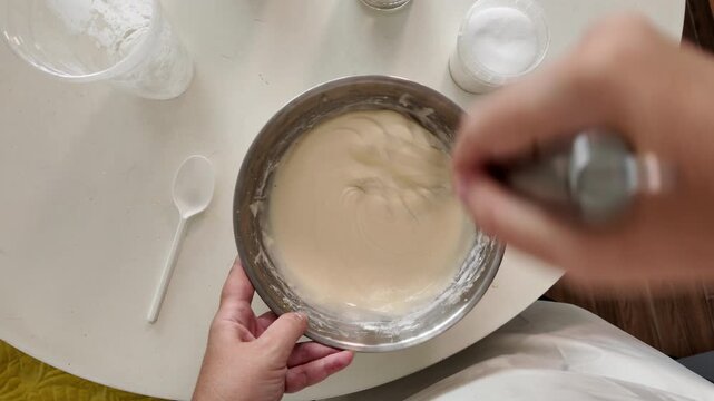 Woman added the ingredients to the batter and whipped the mixture with a whisk