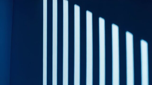 Empty room corner illuminated by strong natural light casting striking vertical and horizontal parallel shadows on the walls and floor, creating a minimalist visual composition