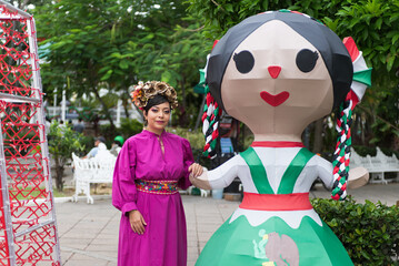 Obraz premium Cheerful Adult Woman Posing with a Traditional Mexican Rag Doll Sculpture