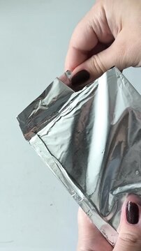 Female hands opening a package of chocolate foil. Dark chocolate in foil