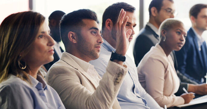 Man, raised hand and audience at convention for business people for questions, insight or feedback. Person, crowd and gesture for review, workshop or group with notes at corporate training conference