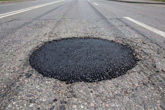 Freshly repaired pothole on an asphalt road