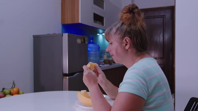 Woman eating melon sitting at a table