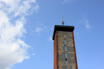 Weathered Communication Tower Against a Blue Sky with Clouds