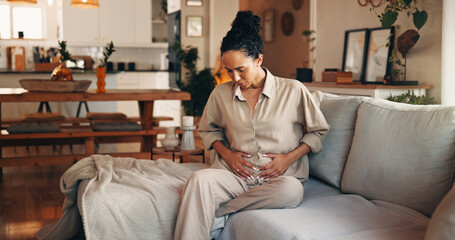 Woman, stomach ache and sofa with pain for indigestion, period cramps or menstruation cycle in...
