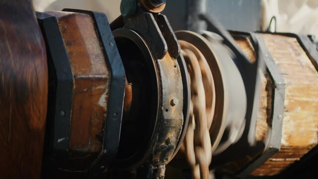 Anchor chain running through windlass on sailing ship during sunset mooring