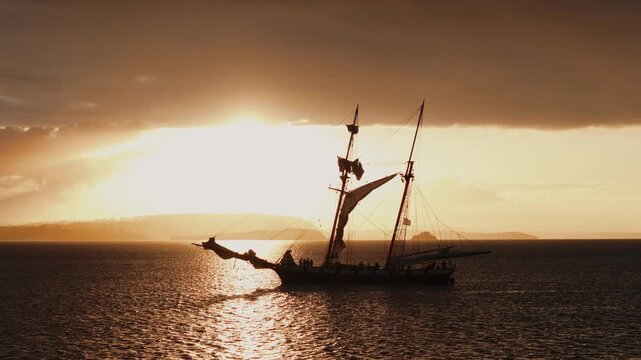 Drone tracking shot of tall ship silhouette at sunrise in Crozon Bay, France