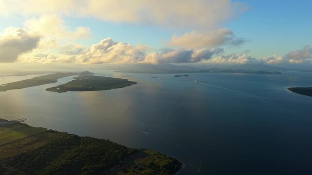 Breathtaking aerial drone footage of cargo ships navigating the calm waters of Paranagu&aacute; Bay in Brazil during a beautiful golden hour sunrise.