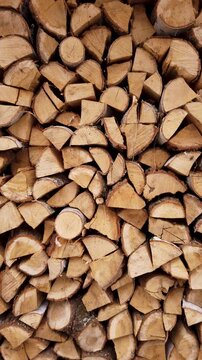 Woodpile of seasoned firewood for rustic winter heating, vertical video