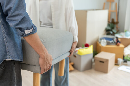 Moving house, relocation. Couple help set sofa and move furniture for new apartment, inside the room was a cardboard box contain personal belongings. move in the new apartment or condominium