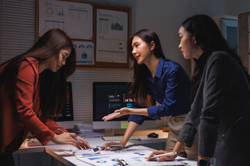 Fototapeta premium Women team analyzing data charts late at night working overtime