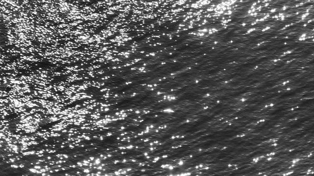 Aerial drone view of dark ocean waves shimmering with sunlight reflections, capturing abstract sea textures, fluid motion, water dynamics, and tranquil marine atmosphere across the surface.