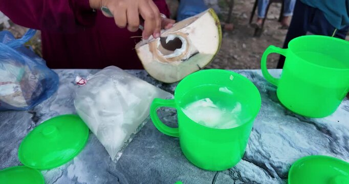 Coconut being cracked open on a table with green cups.