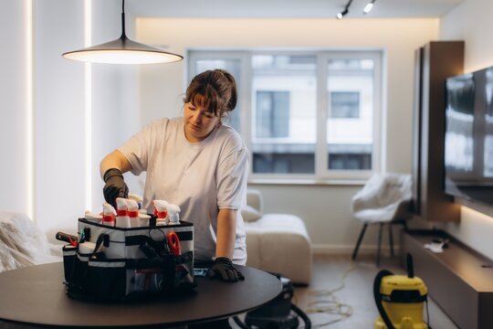 Professional cleaner selecting cleaning bottles from service bag