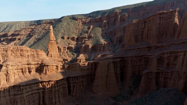Majestic eroded sandstone canyon in Kyrgyzstan, observing towering rock spires. Serene atmosphere evokes a sense of adventure and awe.