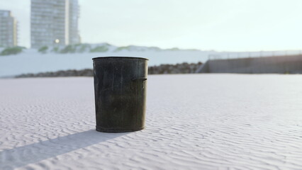 Naklejka premium A solitary trash can stands on a quiet beach at sunrise. The soft sands glisten in the light, while nearby buildings loom in the background, creating a unique contrast.