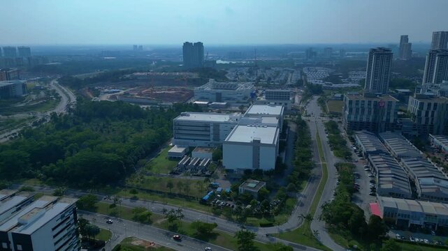 Modern city infrastructure expanding, including data centers, residential buildings, and roads within a rapidly growing Asian urban landscape. Majestic aerial view fly reverse drone