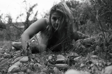 Young blonde woman with an elegant gaze in the forest, black and white portrait