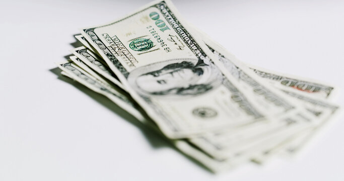 Stack, money and dollars on table in studio for salary, financial fraud and embezzlement. Wages, notes and gambling for illegal cash, illicit funds and scam with income corruption on white background