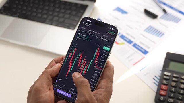 Stock Exchange Broker Analyzing Real-Time Stocks and Exchange Market Charts on Smartphone Using Online Trading App. Investment Agent Working in Office. Close Up.