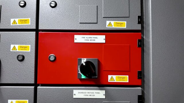 Red fire alarm panel with a black control switch and danger warning labels