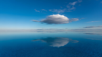 Obraz premium Serene Infinity Pool Reflecting a Single Cloud Under a Vast Blue Sky