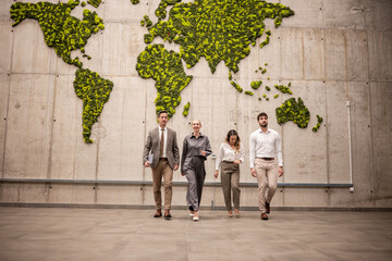 Business people walking past moss world map wall © Zoran Jesic
