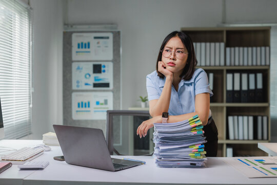 Stressed businesswoman thinking about overwhelming office paperwork