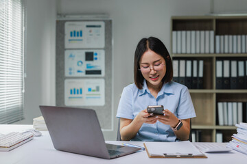 Young businesswoman using smartphone at office desk