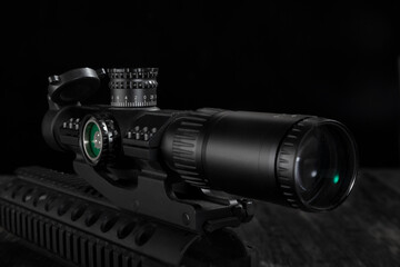 Close up of a tactical rifle scope mounted on a rail system against black background © jianjian