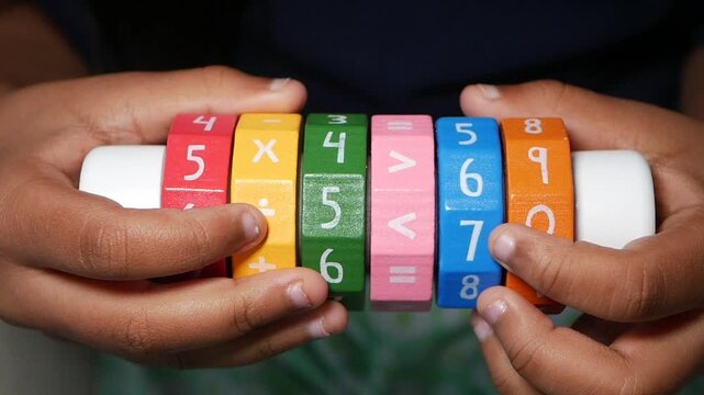 Close up of child's hands playing with colorful wooden math toy with numbers and symbols, educational game for toddlers
