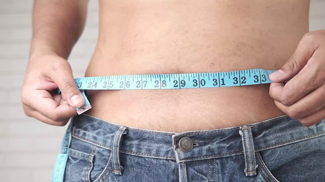 Person measuring waist with tape measure, progress of weight loss journey footage