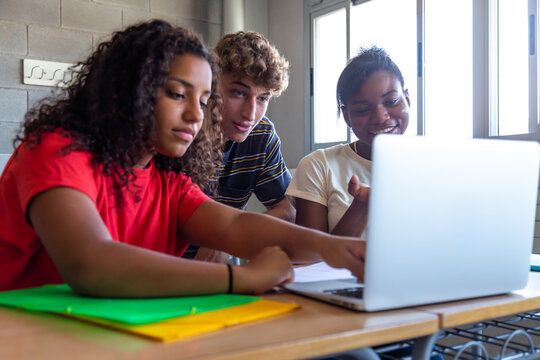 Diverse students collaborating on laptop studying together