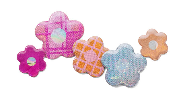 assortment of iridescent holographic flower stickers with patterned surfaces, isolated against a dark background.